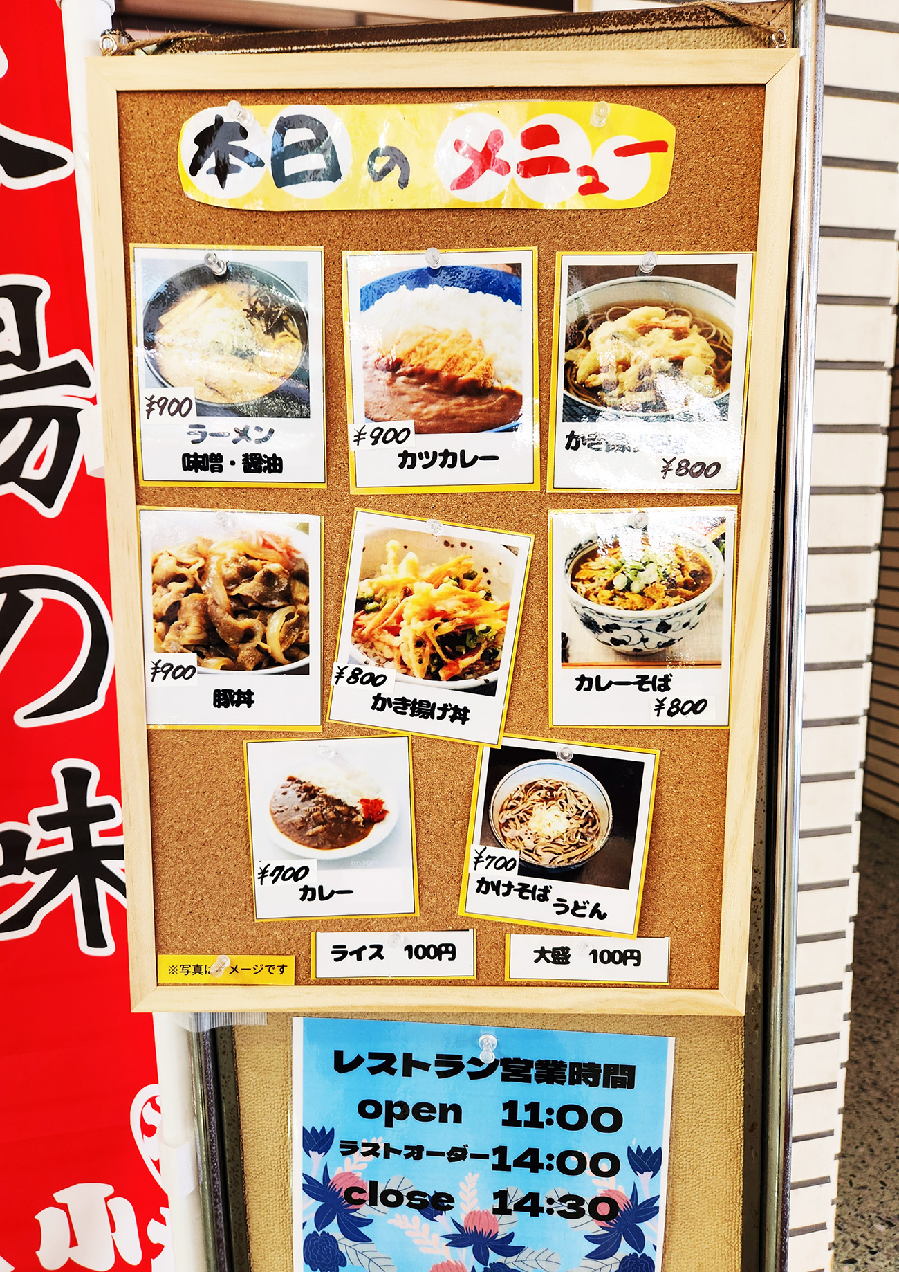 ボードにメニューの写真と価格帯が掲載されている。左上からラーメン味噌・醤油(900円)、カツカレー(900円)、かき揚げそば(800円、豚丼(900円)、かき揚げ丼(800円)、カレーそば(800円)、カレー(700円)、かけそば・うどん(700円)、ライス(100円)。100円追加で大盛にもできるようだ。